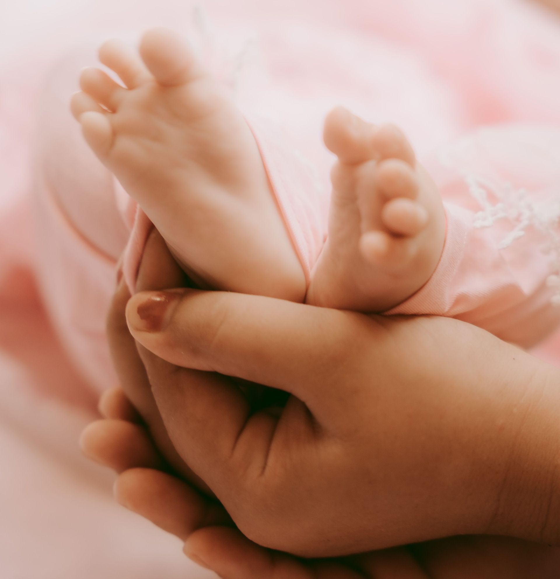 Close-up of a baby's feet held gently by a mother's hands, conveying tenderness and love.