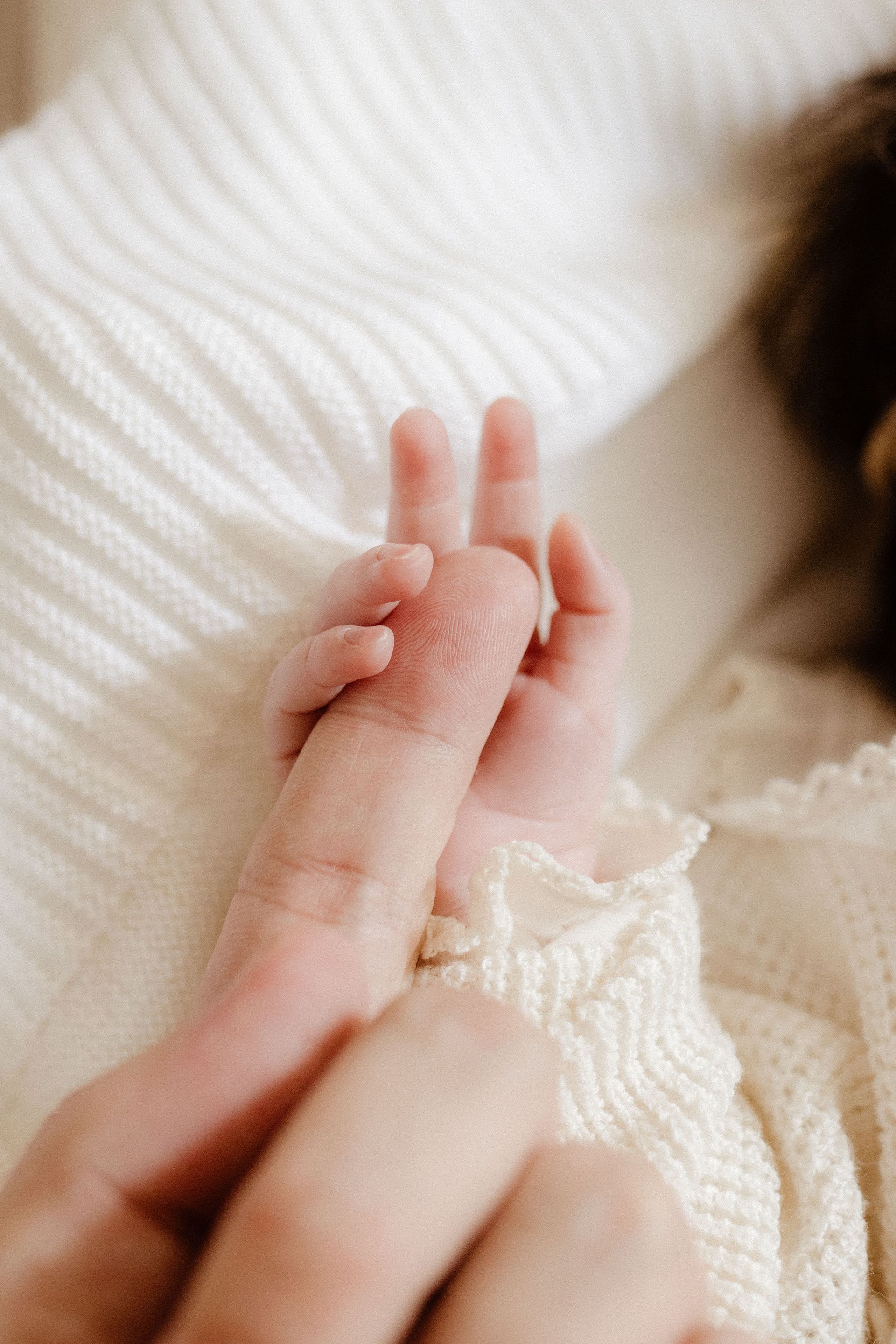 Close-up of baby hand holding parent's finger, symbolizing love and care.
